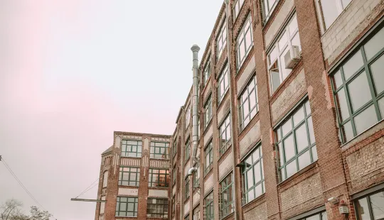 Backsteingebäude mit vielen Fenstern bei rosa Himmel.