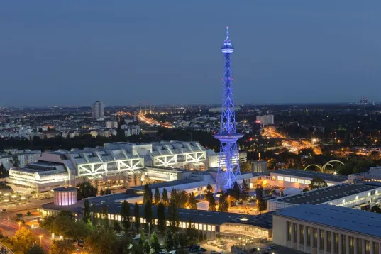 Beleuchteter Funkturm Berlin bei Nacht, umgeben von Messegebäuden und Stadtlichtern.