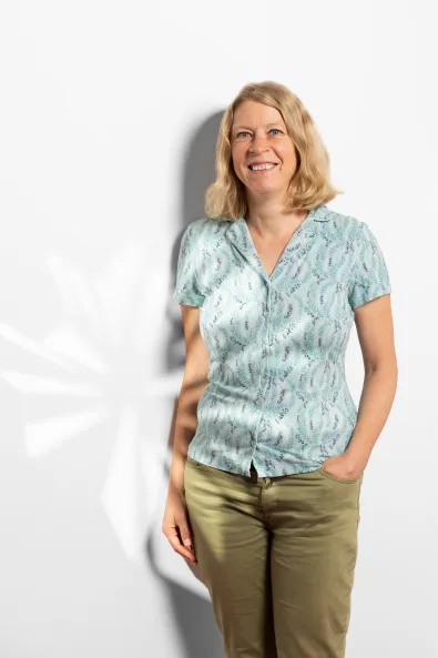 Bild einer lächelnden Frau im blauen Oberteil und grüner Hose, Leonie Umbach, Projektmanagerin Sustainable Berlin im Berlin Convention Office