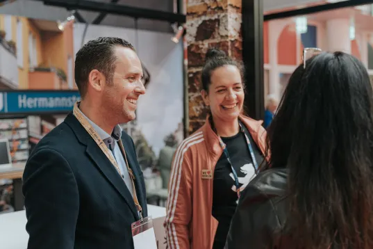 Mitarbeitende des visitBerlin Berlin Convention Office im Gespräch mit Partnerinnen auf einer Messe